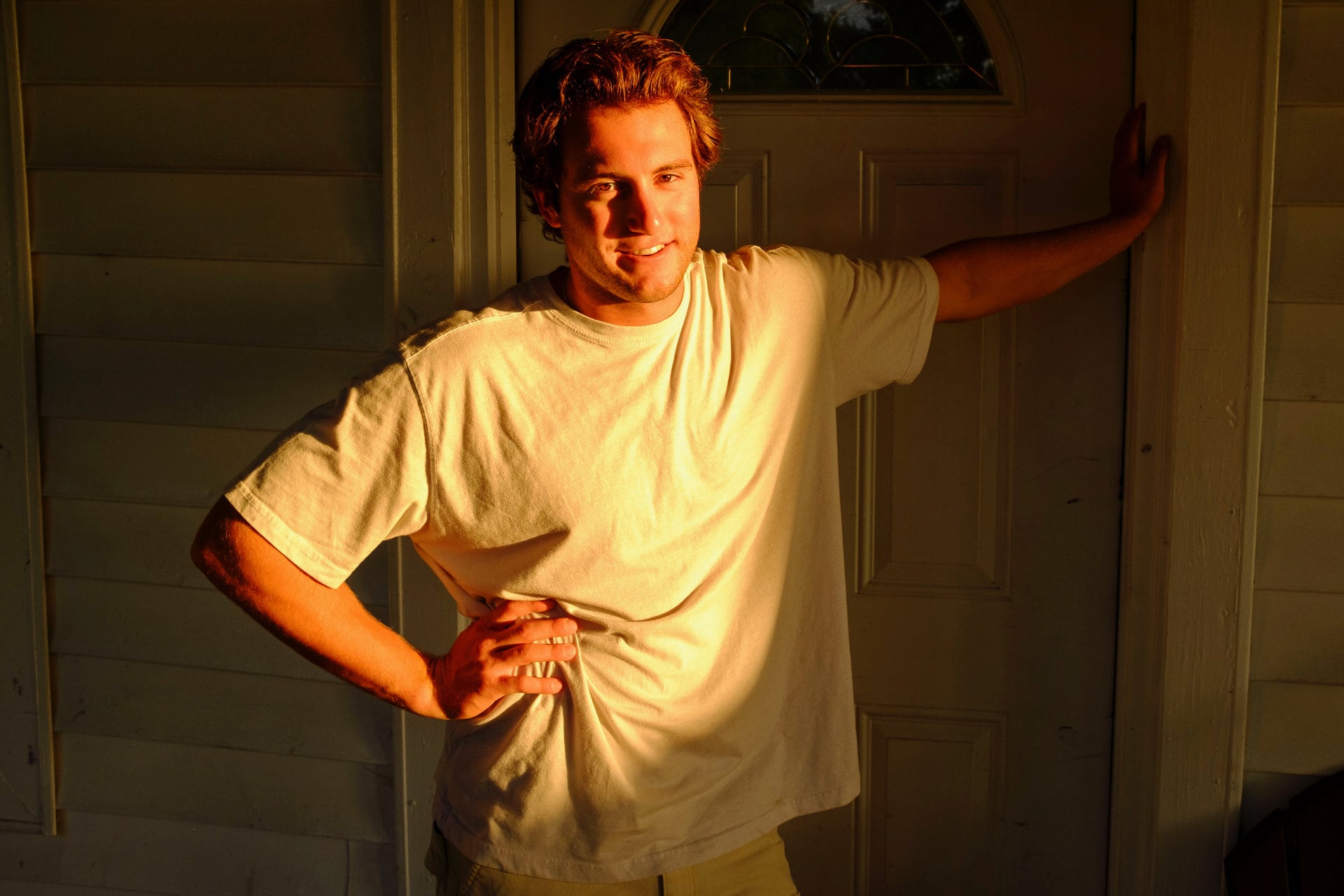 Dante DeRosa leaning in a doorway, lit by warm evening light